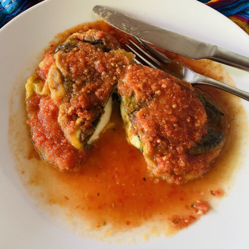 Chile Relleno with Cheese on a plate, cut in half with a Mexican rebozo in the background