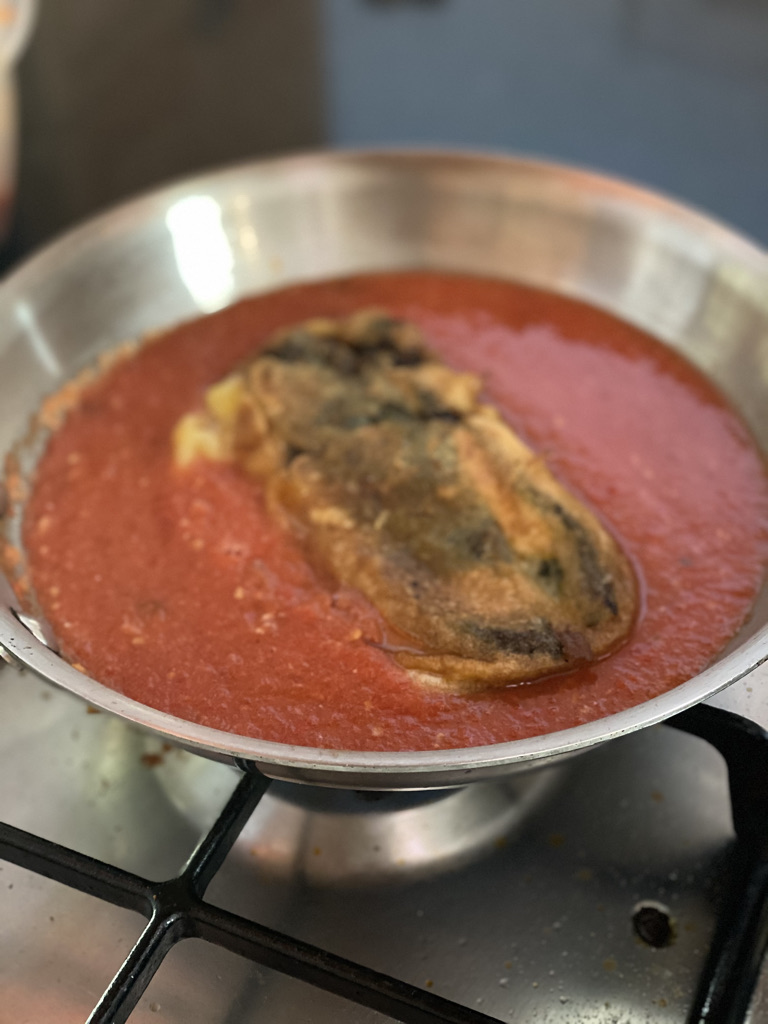 Chile relleno simmering in sauce