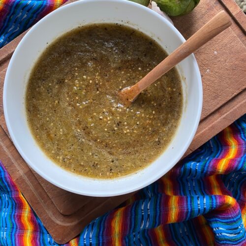 Roasted Salsa Verde in a white bowl, sitting on top of a wooden cutting board with a colorful Mexican rebozo on the side