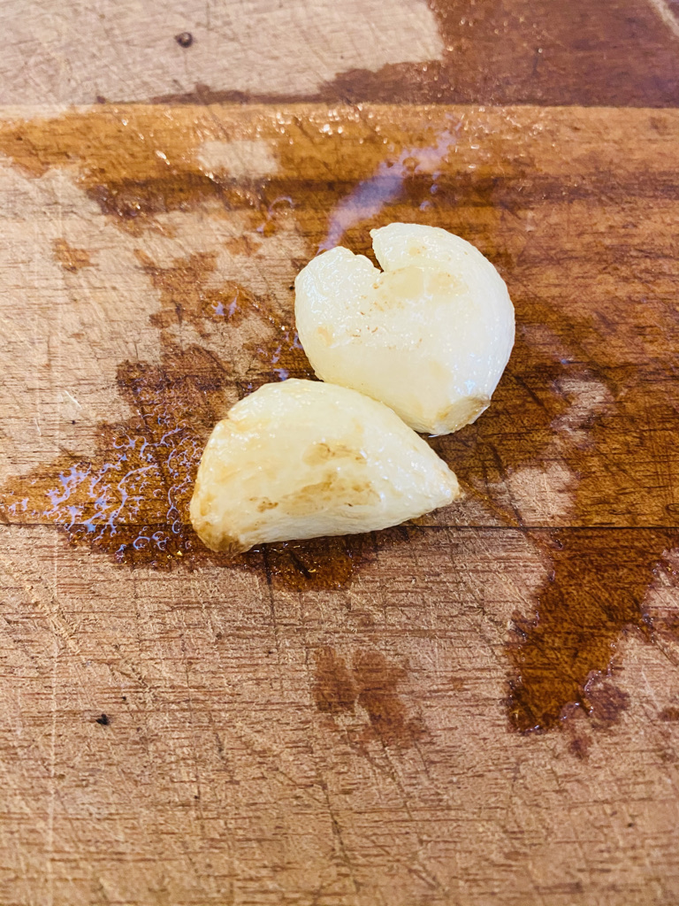 Fried garlic cloves on a wooden cutting board