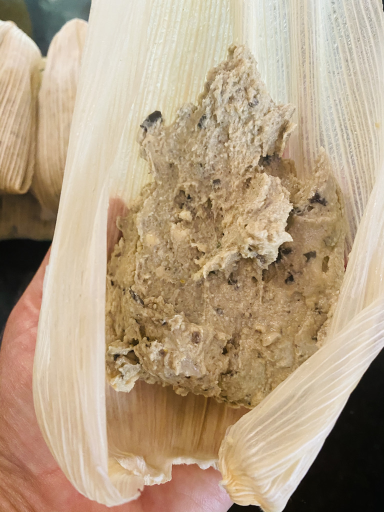 Filling a corn husk with black bean masa