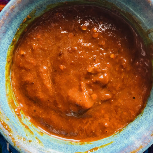 Close up chile morita salsa in a blue pottery dish on a colorful Mexican rebozo