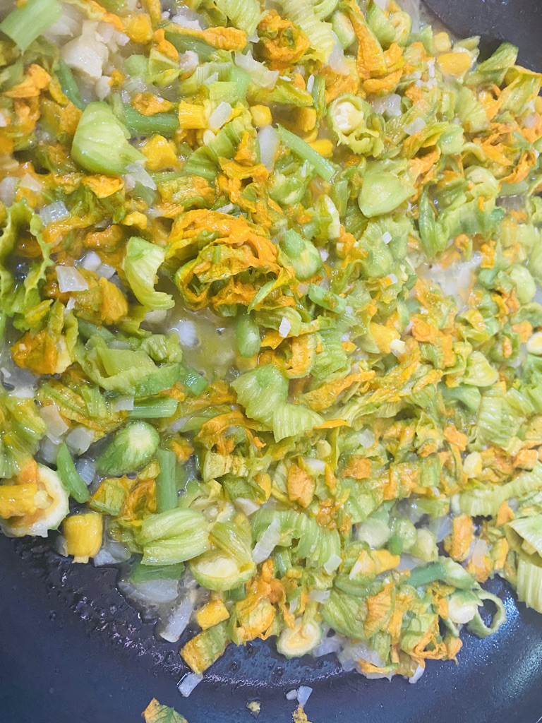 Squash blossoms cooking with onions and garlic