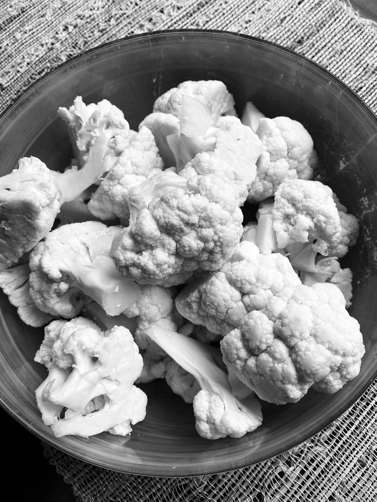 Black and white photo of cut up cauliflower in a bowl