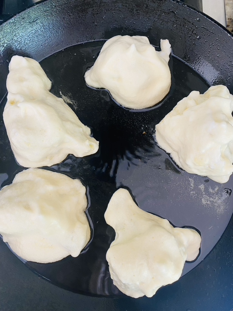 Cauliflower pieces that have been battered are fried in a non-stick skillet in a bit of oil