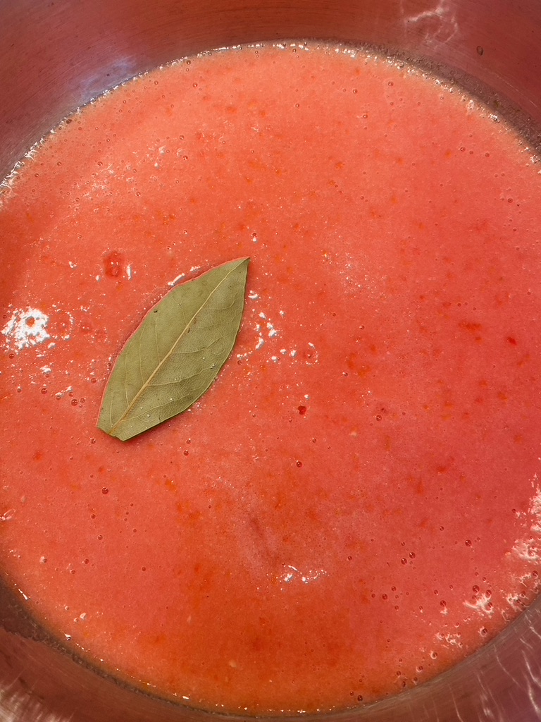 Tomato sauce added to pan with bay leaf to begin cooking