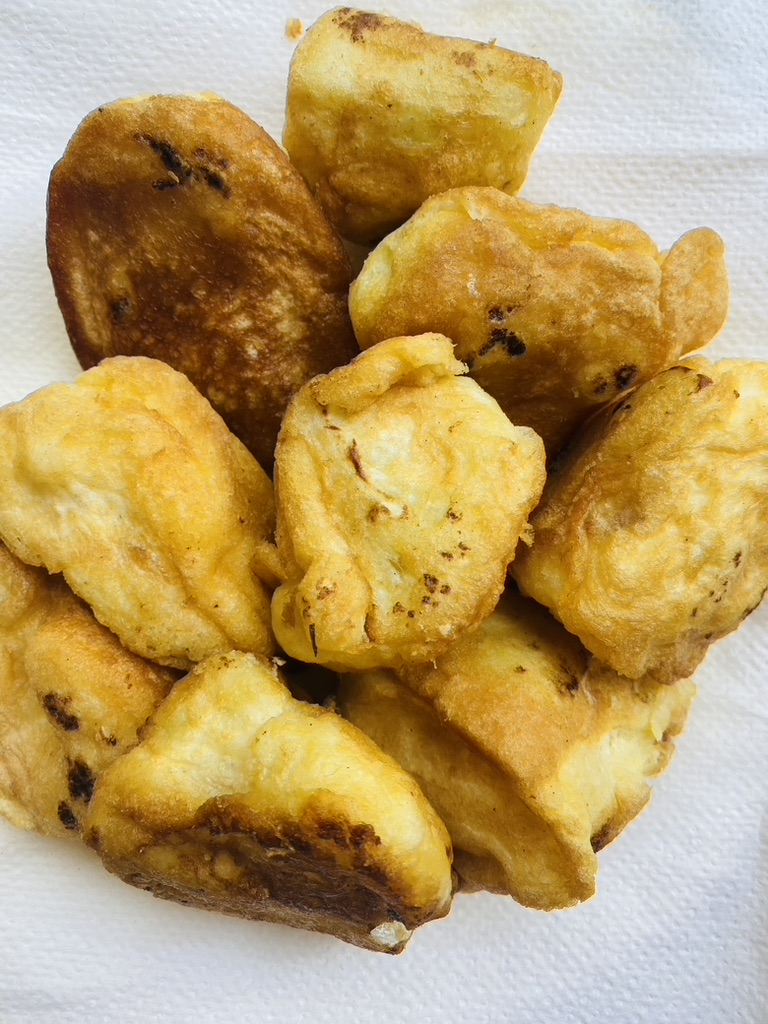 Fried cauliflower pieces are drained on a paper towel-lined plate