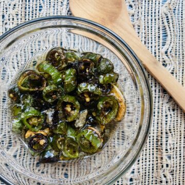 Glass bowl filled with sliced and fried serrano chiles in oil