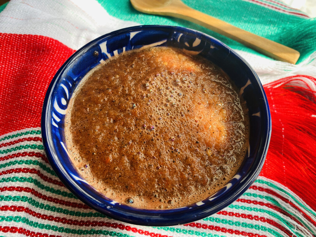 Charred Salsa Roja in a blue talavera bowl on a red, white, and green cloth
