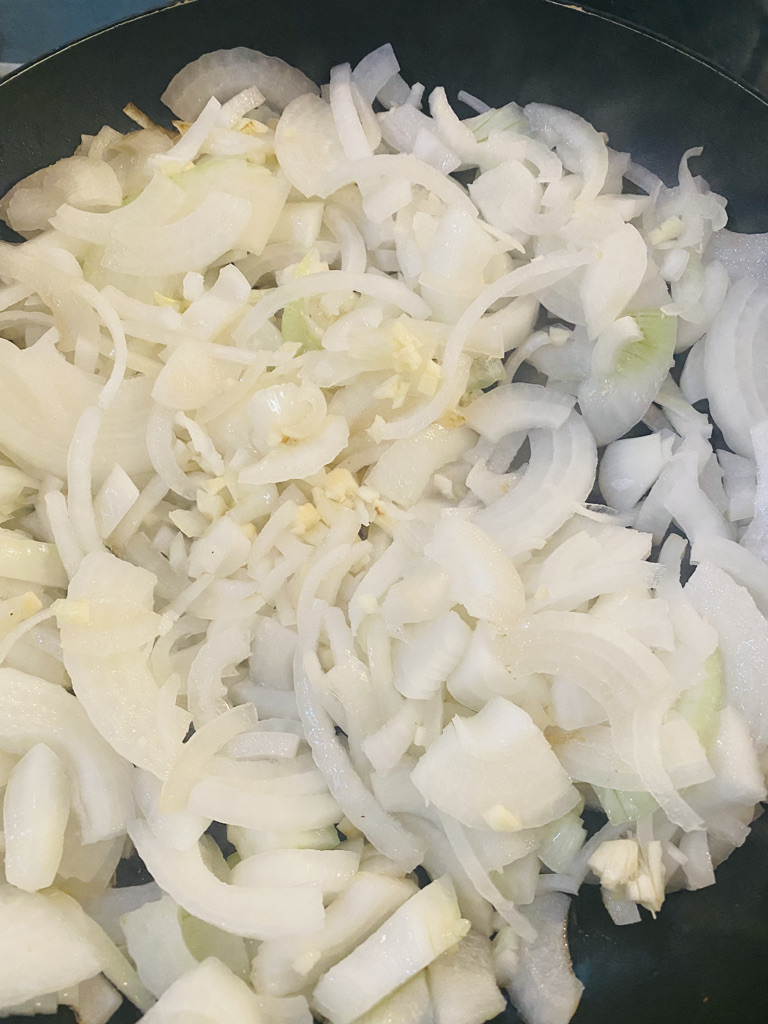 sliced onions frying in a large skillet