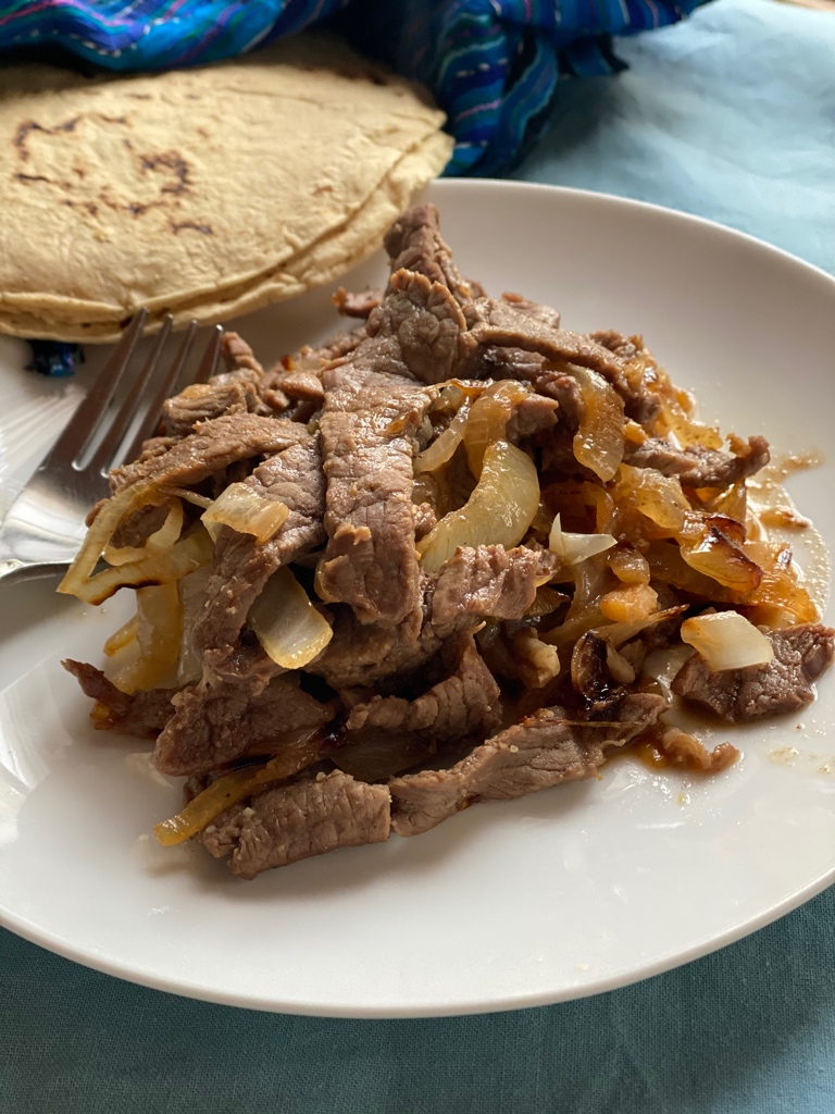 Plate of Mexican steak and onions with corn tortillas