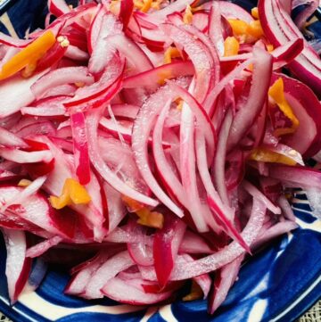 Strips of red onion and habaneros in a blue pottery bowl