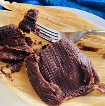 Chocolate tamal on a white plate with a fork