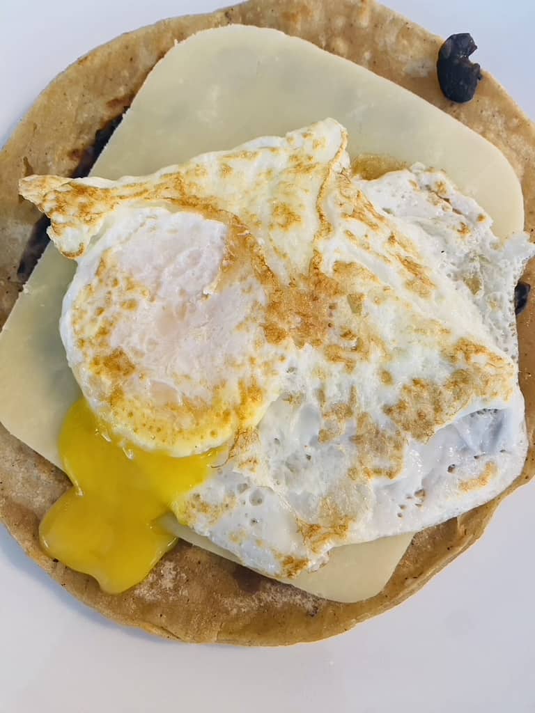 Egg on top of a bean and cheese tostada