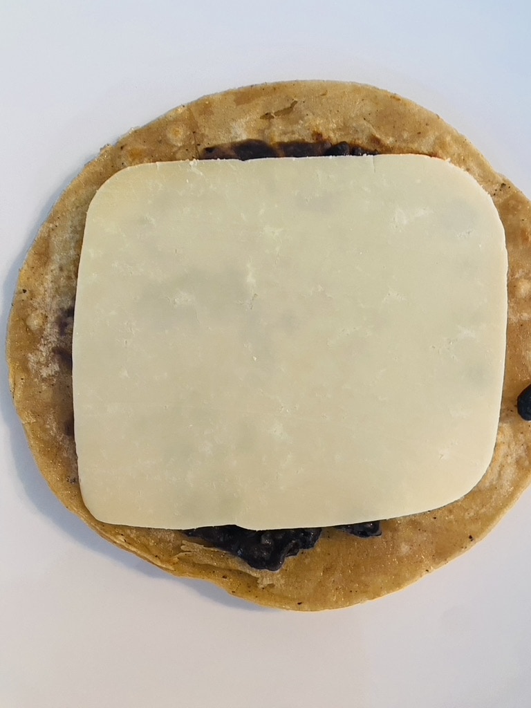 Fried corn tortilla topped with black beans and cheese