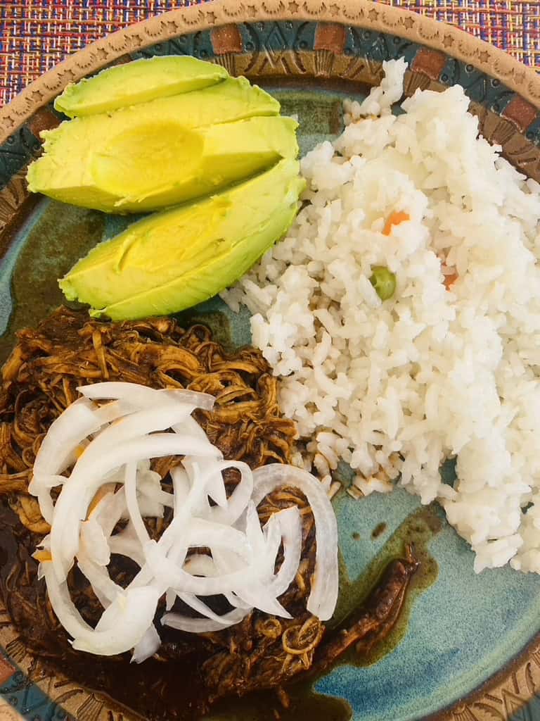 Saucy Mexican shredded chicken with pickled onions and avocado slices