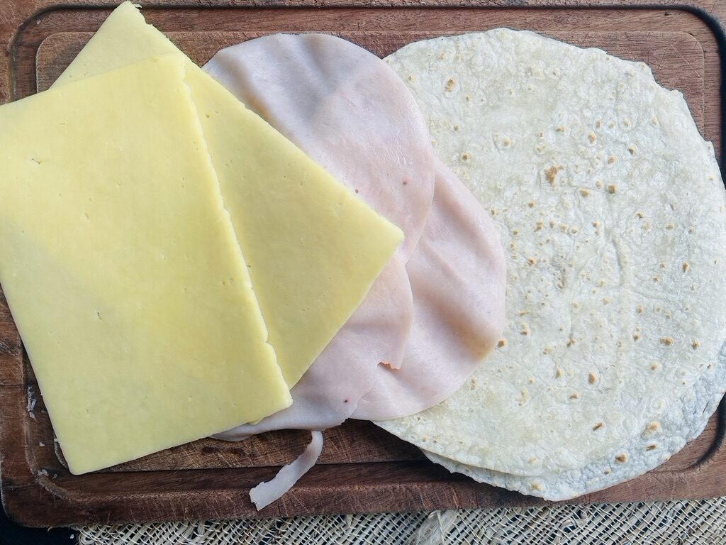 Sincronizada ingredients, slices of cheese, slices of ham, and flour tortillas