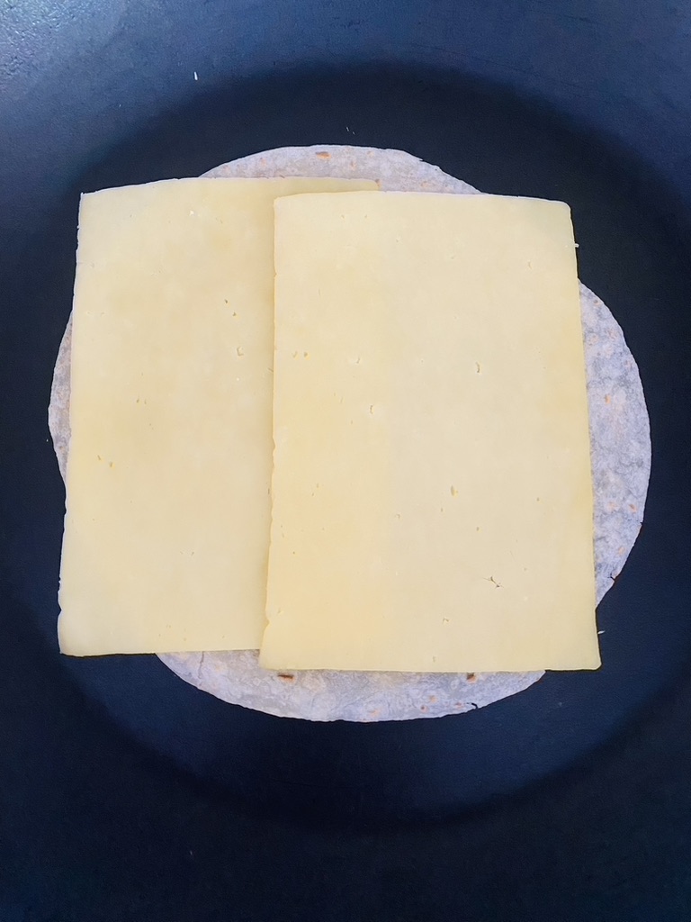 Flour tortilla in a non-stick skillet topped with 2 slices of cheese