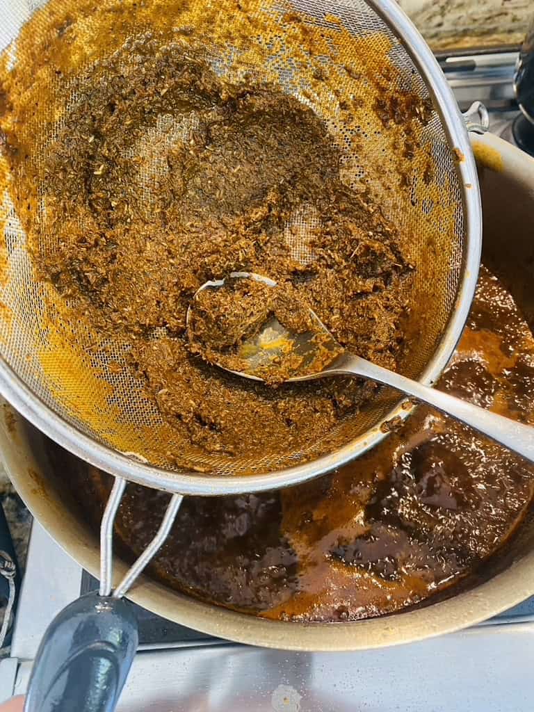 Use spoon to help push sauce through fine meshed sieve