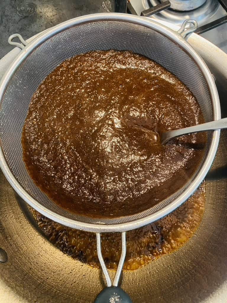 Strain pasilla chile sauce over pan