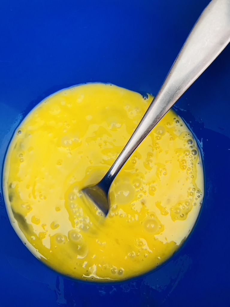 Eggs beaten with a fork in a blue bowl