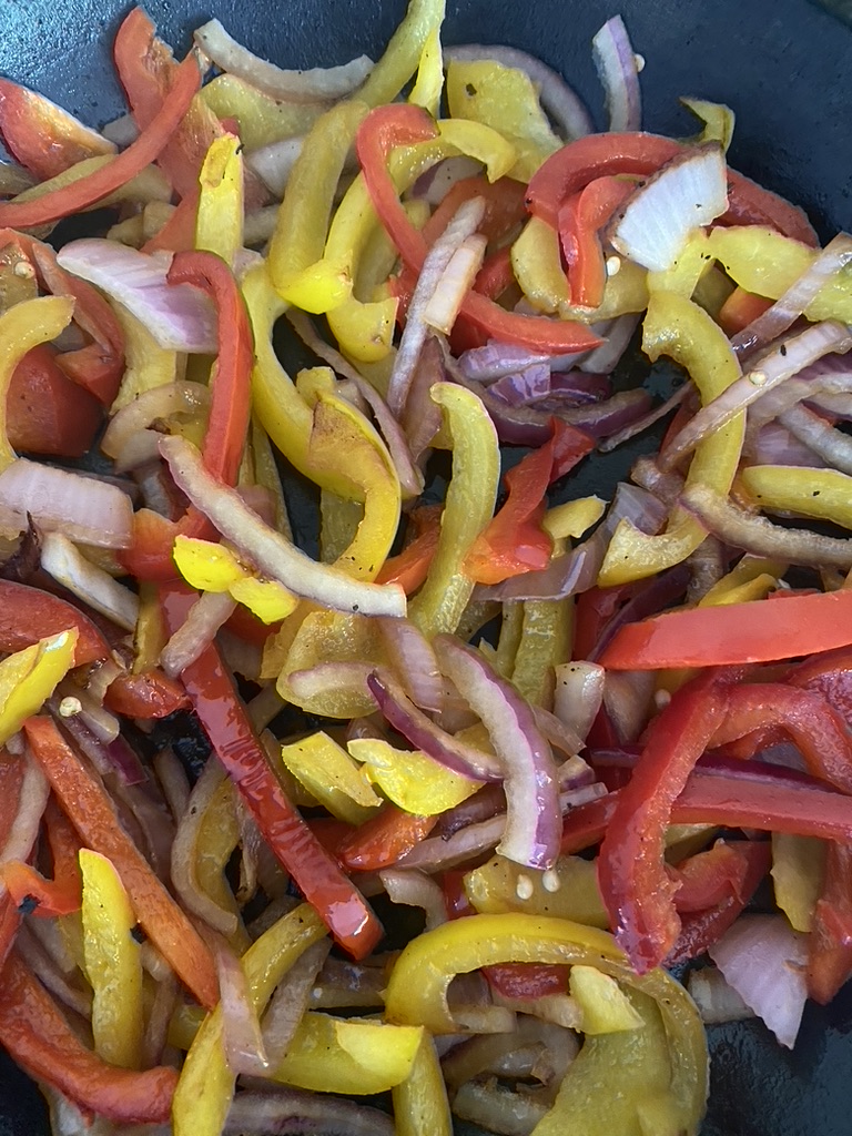 Red onions, and bell pepper strips cooking in a non-stick skillet