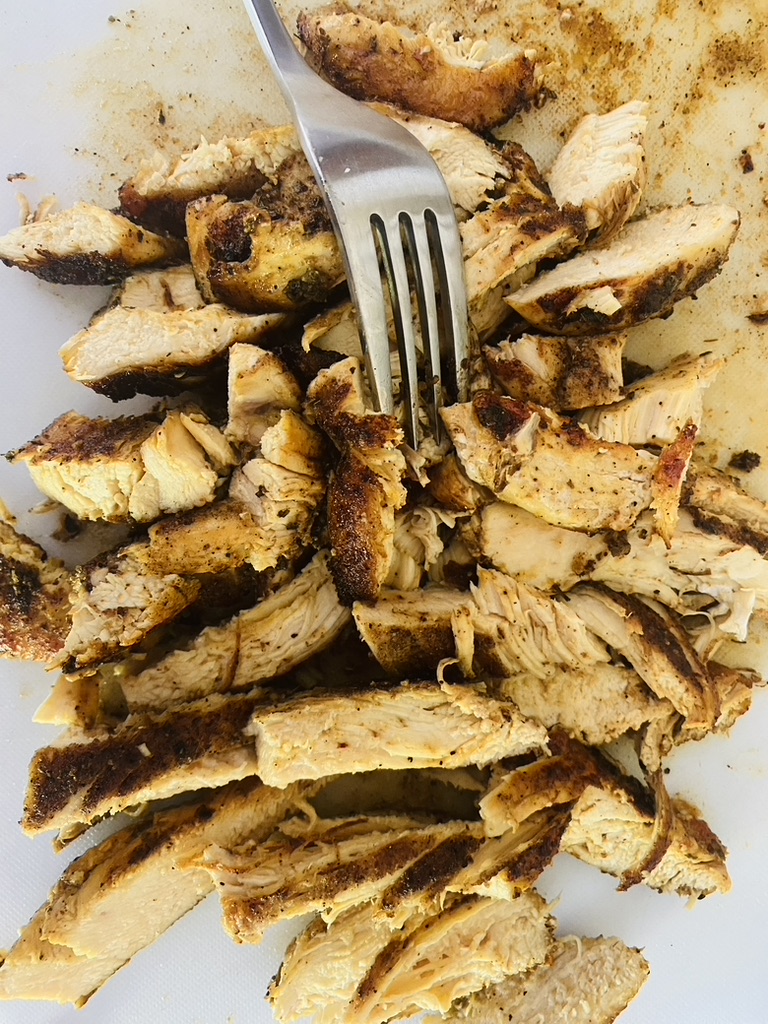 Chicken for fajitas sliced into thin strips on a white cutting board
