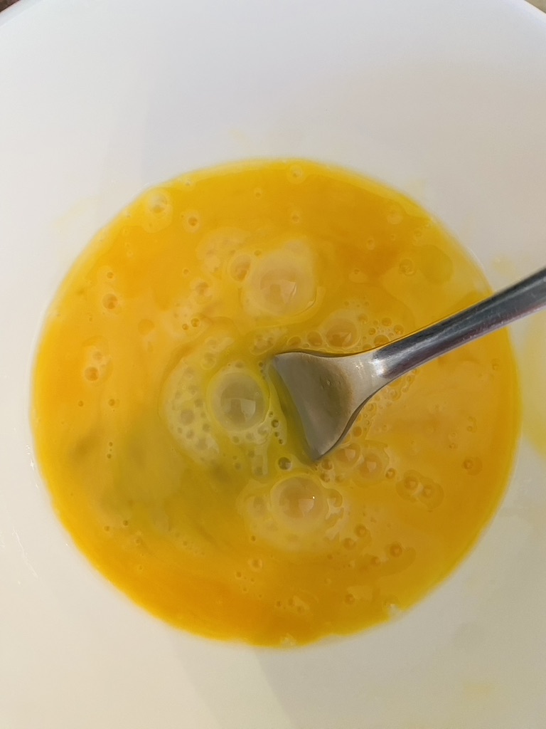 2 eggs mixed in a white bowl