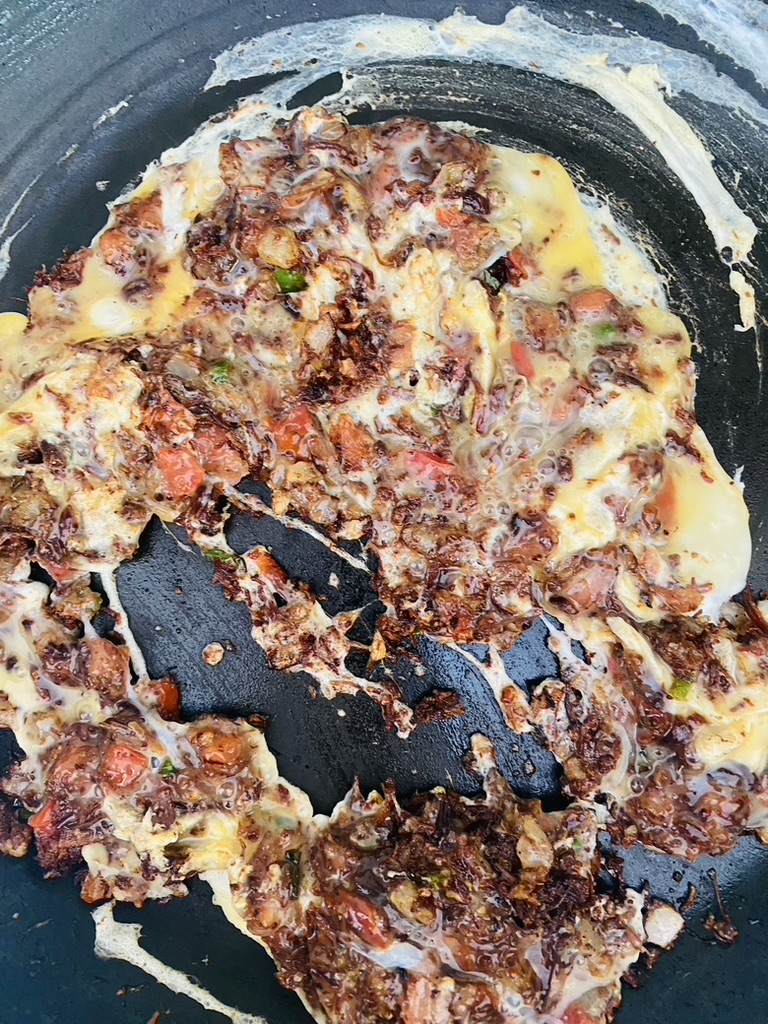 Machaca, garlic, eggs, onions, peppers, and tomatoes in a frying pan