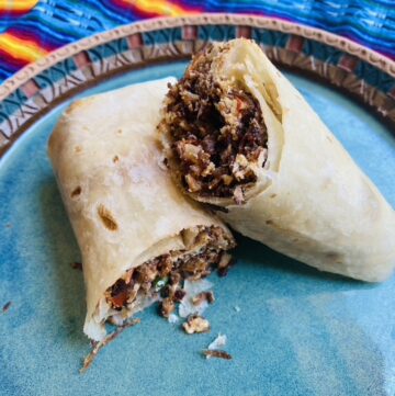 Blue pottery plate with a machaca and egg burrito cut in half