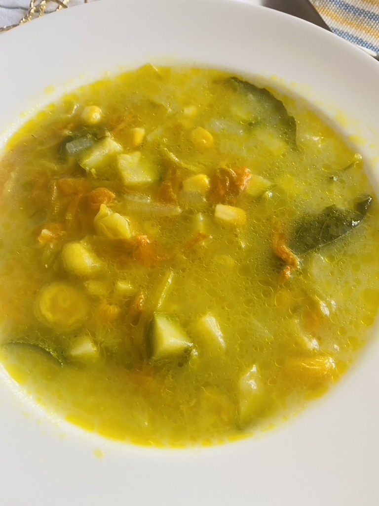 Close up of squash blossom soup in a white bowl