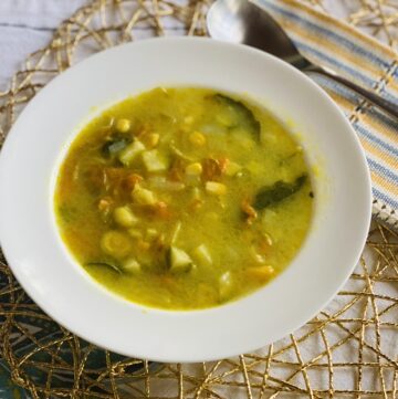 White bowl with squash blossom soup on a golden placemat