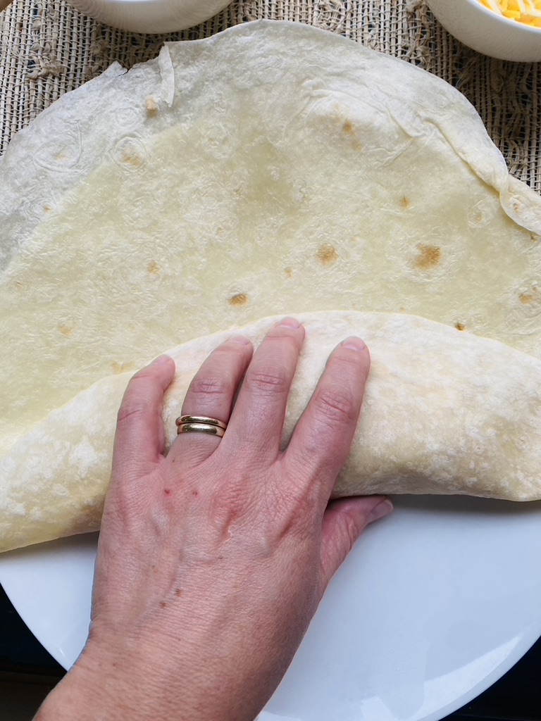 First step in rolling a burrito, fold bottom of tortilla over ingredients