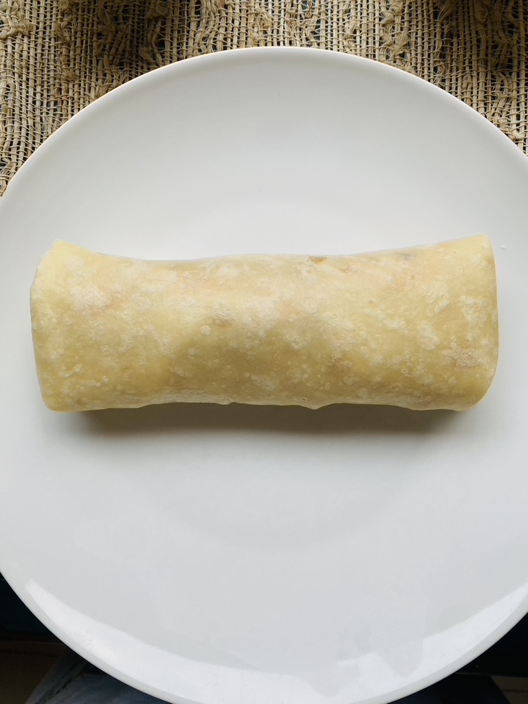 Fully rolled burrito on a white plate