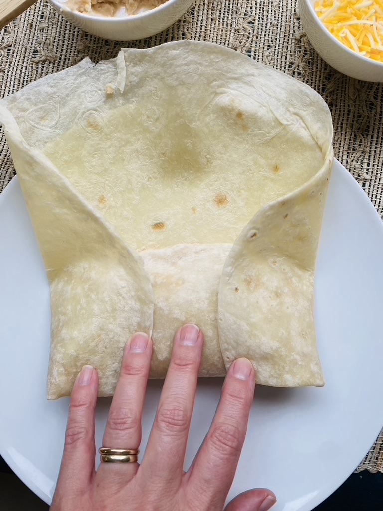 Second step to rolling a burrito, fold sides of tortilla towards center