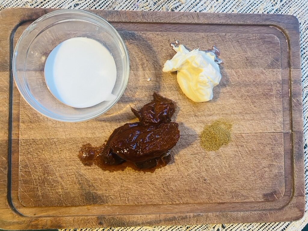 Mexican cream, mayonnaise, chipotle peppers, ground cumin on a wooden cutting board