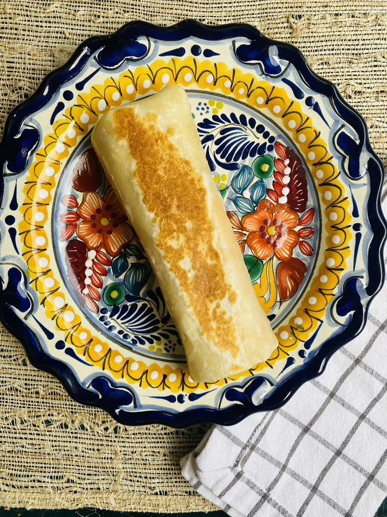Toasted whole burrito on a colorful Mexican talavera plate