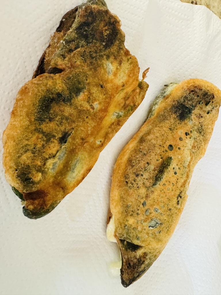 2 golden chile rellenos on a papertowel