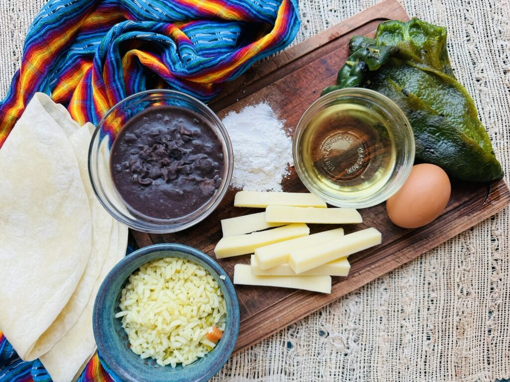 Wooden cutting board with chile relleno burrito ingredients