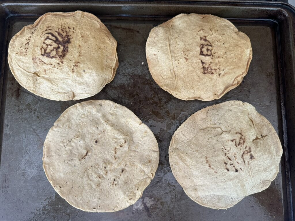 4 baked tortillas on a baking sheet