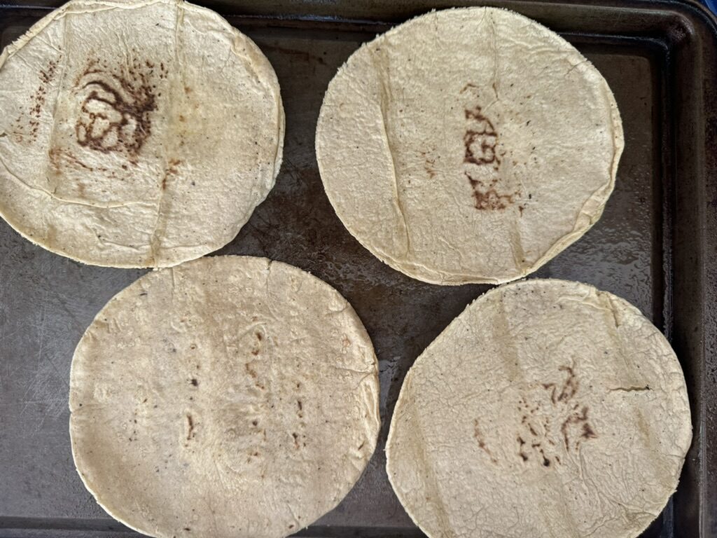 4 corn tortillas on a prepared baking sheet