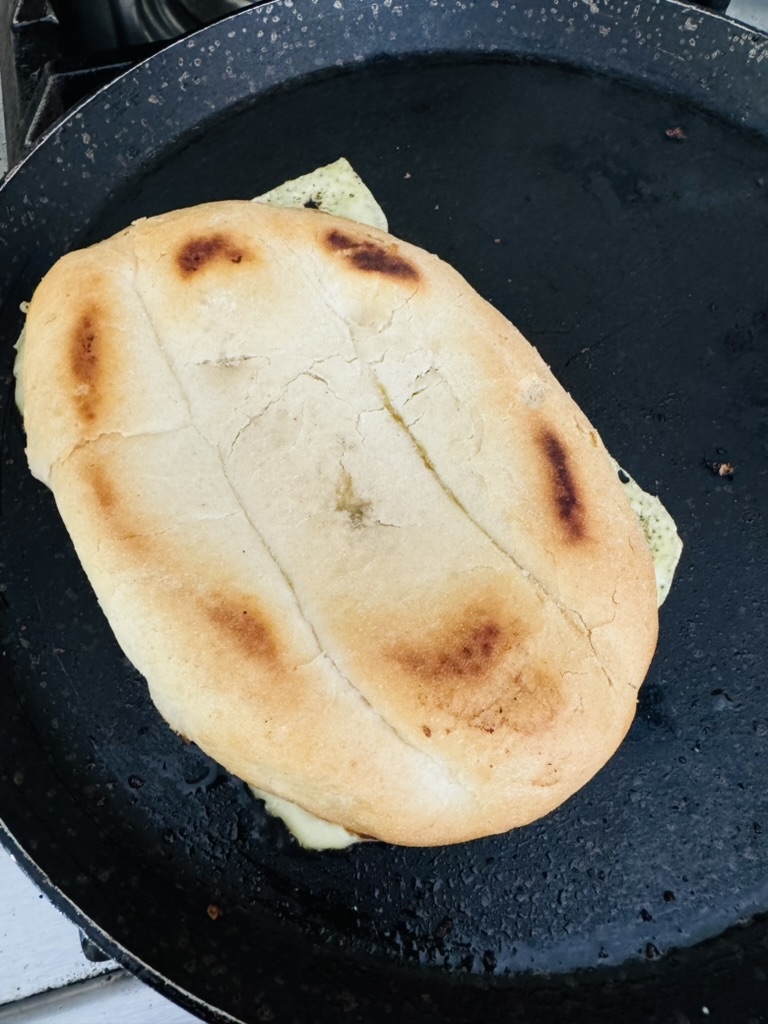 Telera bread with refried beans and cheese, cheese side down in a skillet