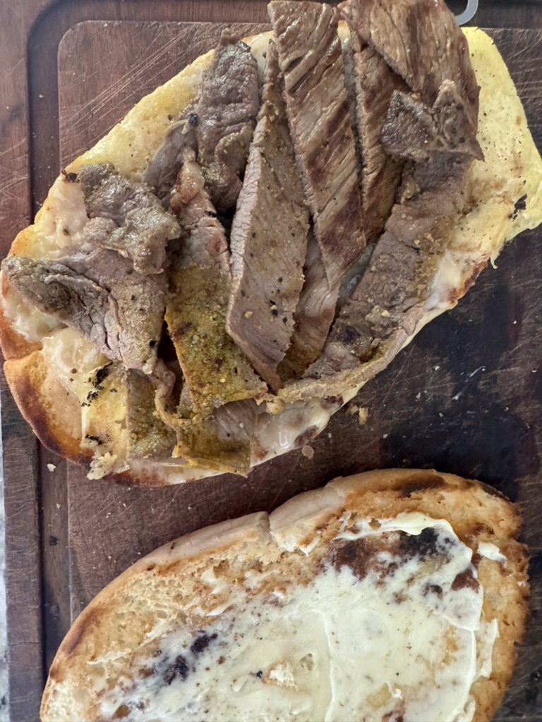 Steak sliced in strips on top of melted cheese and refried beans