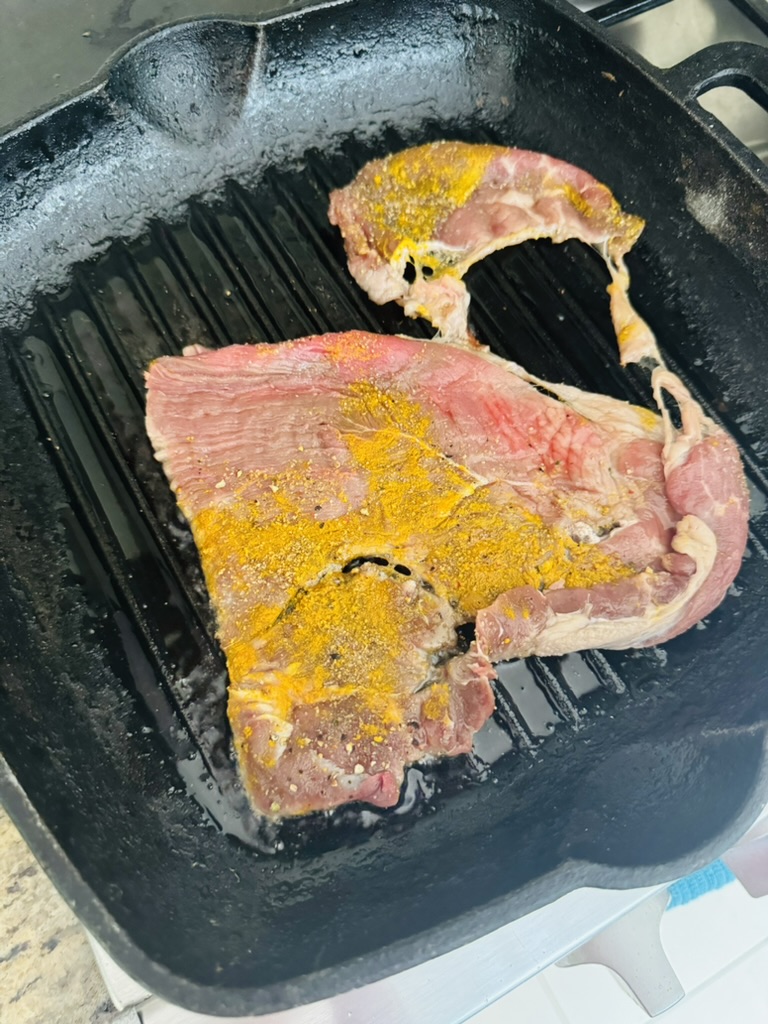 Thinly sliced and seasoned sirloin steak cooking in a grill pan.