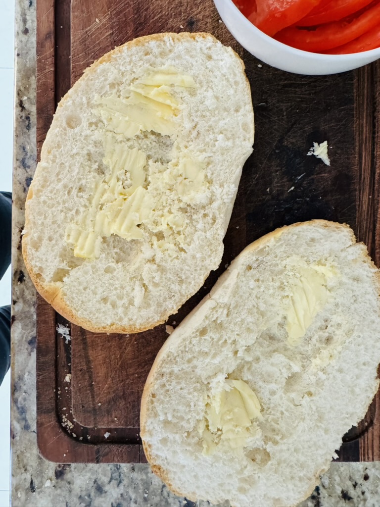 Buttered slices of telera bread on a wooden cutting board