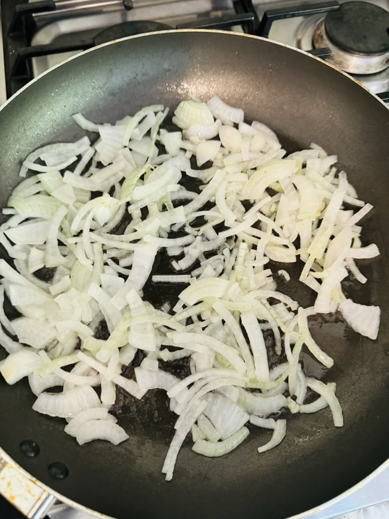 Sliced onions frying in a non-stick skillet