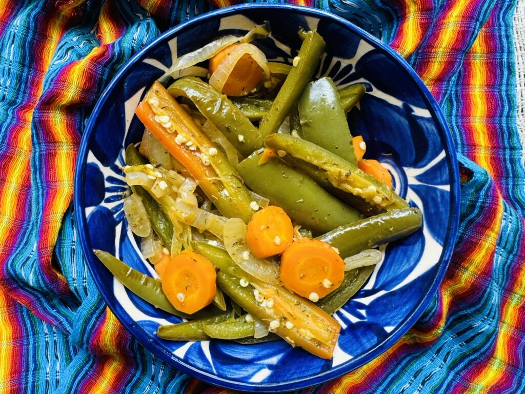 Pickled jalapeño peppers, carrots, and onions in a blue pottery bowl