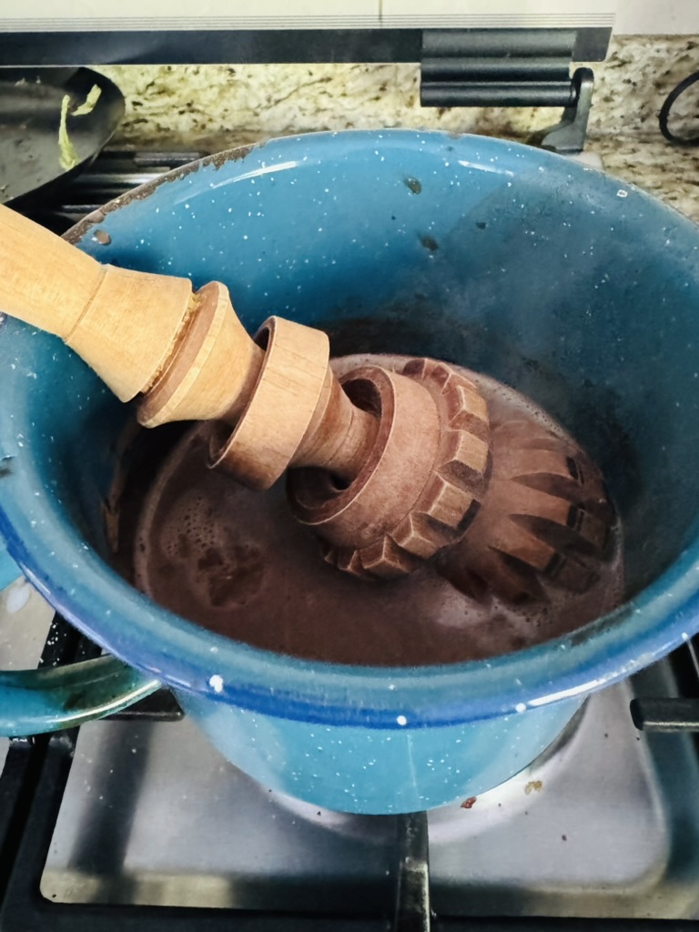 Hot chocolate in a blue pot with a molinillo
