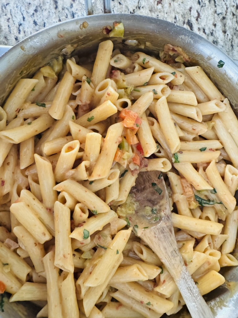 Penne pasta being mixed in to the creamy chipotle sauce