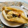Vegan corn husk tamal with chile strips and cheese on a white plate